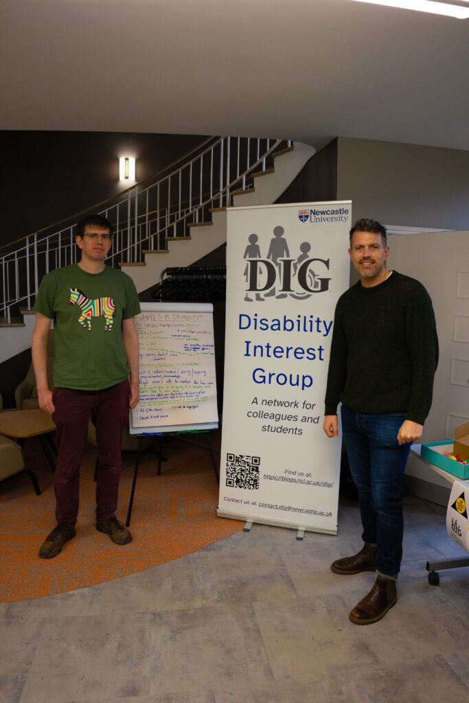 Christian and Kevin stood in front of a flipchart and Disability Interest Group banner