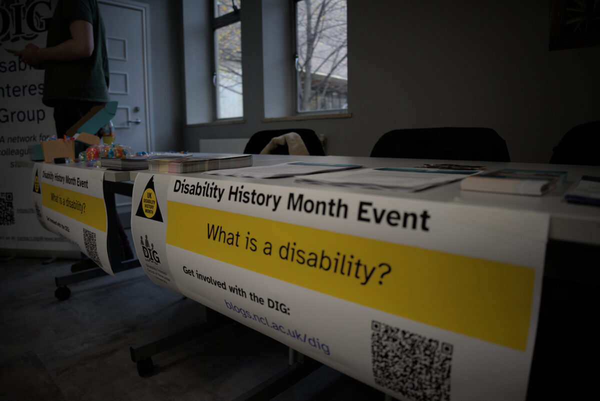 A table with flyers and fidget toys on top, and a banner reading "Disability History Month Event", hanging off the front.