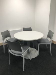 A photo of the small meeting room showing a round table and four chairs.