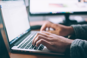 A photo of hands typing on a laptop keyboard.