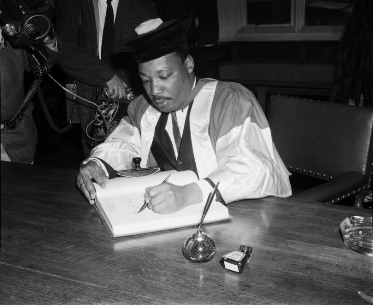 Photograph depicts civil rights activist Dr Martin Luther King signing the visitors' book during his visit to Newcastle University to accept an honorary doctorate of Civil Law on 13th November 1967. 