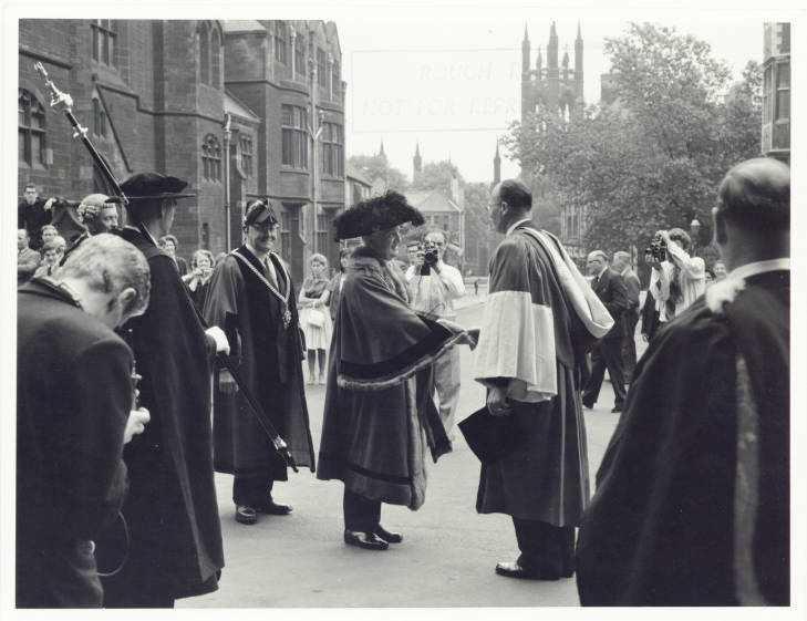 Photograph of the Ceremony on the official establishment of Newcastle University. Shows The Lord Mayor of Newcastle, Alderman Harry Simm, and the Vice Chancellor of Newcastle University Charles Bosanquet shaking hands on the day the University of Newcastle upon Tyne formally became a separate entity to Durham University. 