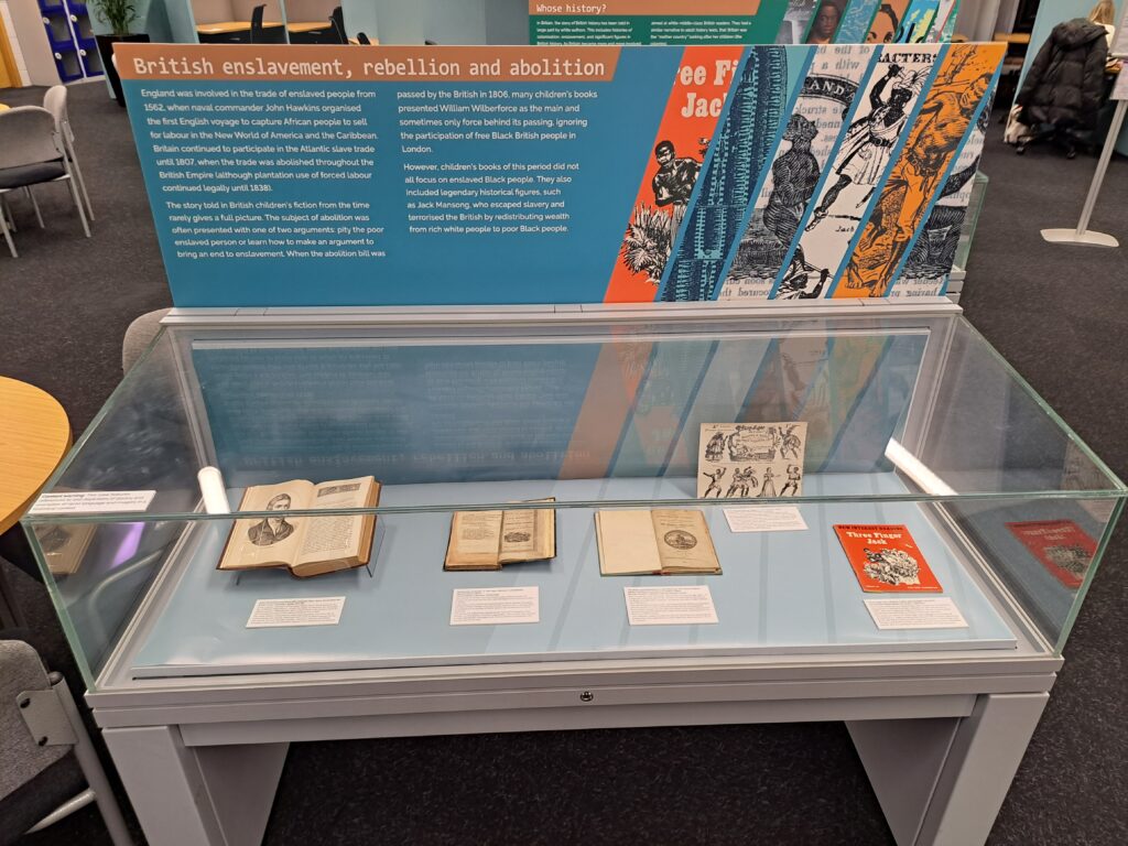 'British enslavement, rebellion and abolition' case used in the Listen to this story! exhibition. Case includes a backing panel with title, text and images with a glass exhibition space in front, with 5 archival items (mainly books) and accompanying paper text captions.