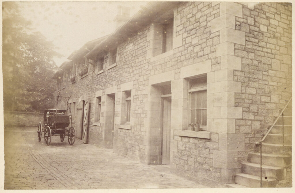 Sepia photograph of workers’ buildings and sheds which have been converted to homes known as Nazareth Mews. They are now isolated from the main house, c. 1890s