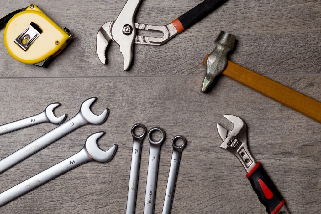 Photograph of tools, including a hammer, spanner and measuring tape, laid out on a table